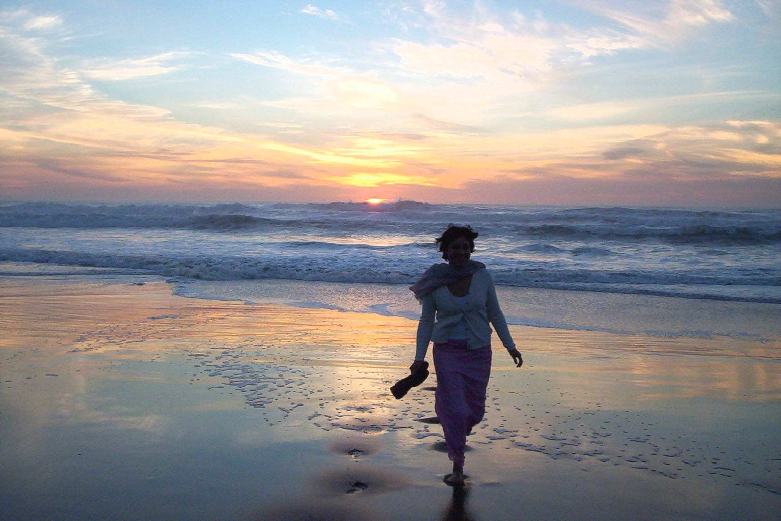 A woman walking along a beach at sunset, photographed by Wise Media Creative